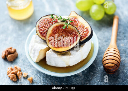 Camembert or brie cheese with figs, honey, grapes on blue background Stock Photo