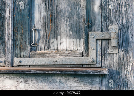 Close-up detail of traditional weather-worn blue painted wood windos shutter with metal hinge and latch Stock Photo