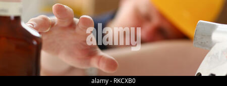Arm of drunken worker in yellow helmet Stock Photo