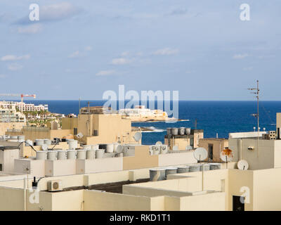 Looking out over the rooftops in the densely built up and populated Saint Julians in Malta, onto the blue Mediterranean sea with the Casino inn the mi Stock Photo