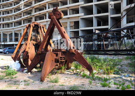 Rusty crane grabbers in front of abandoned hotel in Montenegro. Stock Photo