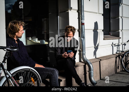 Two friends enjoying the sunny weather in a window frame in Oslo, Norway Stock Photo