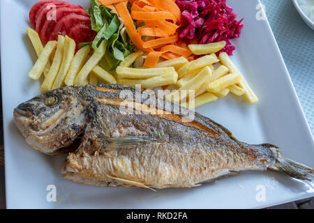 Plate of sea bream fish with French fries and salad in Turkey. Stock Photo