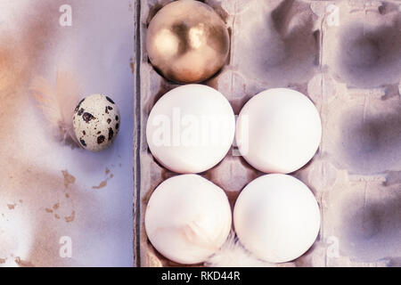 one gold egg lays among common white eggs and quail egg in tray Stock Photo
