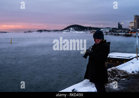 Photographer checking his camera standing on a pier in Oslo on an extremely cold morning. Stock Photo