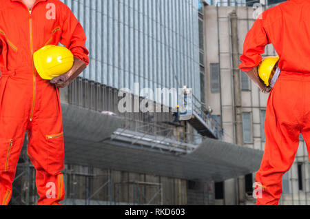 Asian engineers holding a yellow hardhat on photo blurred of construction site workers, industrial construction concept Stock Photo