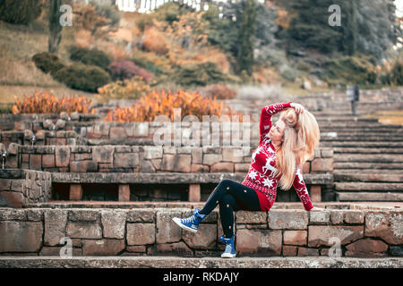 Woman sitting on stone steps in an autumn park. Stock Photo