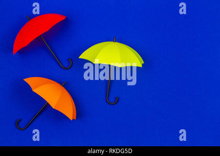 Small colorful umbrellas on blue color background Stock Photo