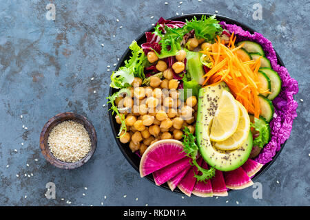 Salad Buddha bowl with fresh cucumber, avocado, watermelon radish, raw carrot, lettuce and chickpea for lunch. Healthy vegetarian food. Vegan vegetabl Stock Photo