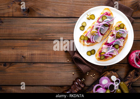 Delicious grilled sandwiches with herring, onion and beetroot sauce with horseradish on dark wooden rustic background. Danish cuisine. Top view Stock Photo