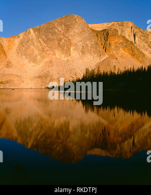 USA, Wyoming, Medicine Bow Routt National Forest, Sunrise on Medicine Bow Peak reflects in calm water of Lake Marie in the Snowy Range. Stock Photo