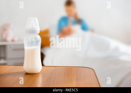 close-up view of baby bottle with milk and mother breastfeeding newborn baby in hospital room Stock Photo