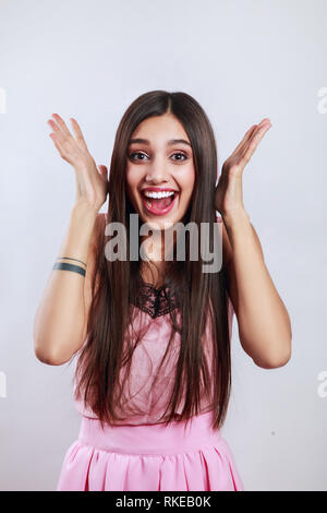 Beautiful brunette woman surprise showing product . Presenting your product. Isolated on gray background. Expressive facial expressions Stock Photo