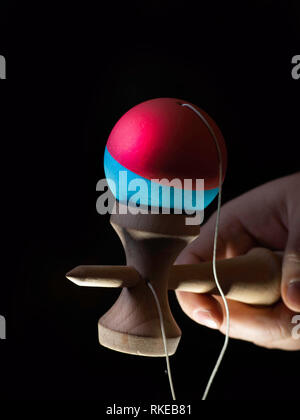 Classic Japanese game kendama on black background. Two boys hands playing kendama Stock Photo