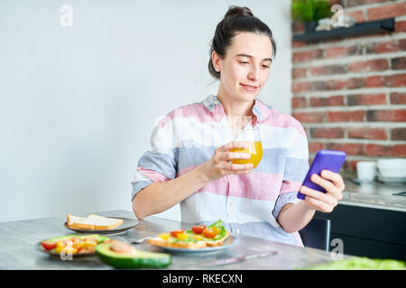 Woman Using Smartphone at Breakfast Stock Photo