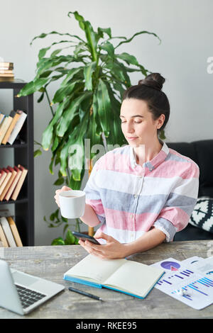 Woman using Smartphone at Workplace Stock Photo