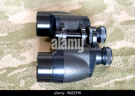 Vintage Porro prism black color army binoculars on camouflage background side view close up Stock Photo