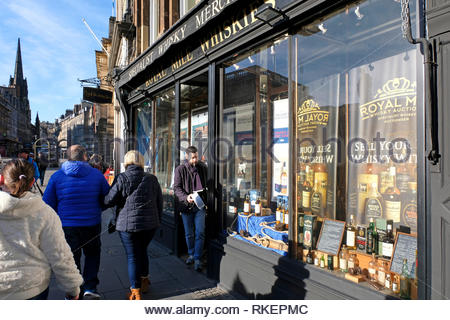 Edinburgh, United Kingdom. 11th February 2019. Cold February day with blue skies. Visitors outside Royal Mile Whiskies on the Royal Mile. Credit: Craig Brown/Alamy Live News Stock Photo