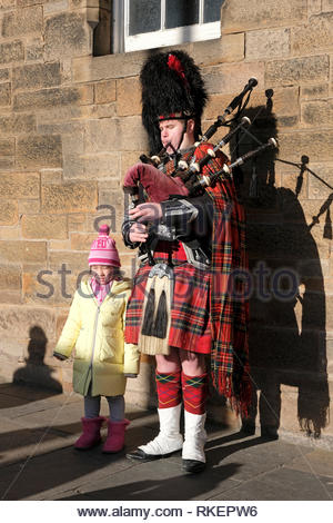 Edinburgh, United Kingdom. 11th February 2019. Cold February day with blue skies. Piper and tourists on Royal Mile. Credit: Craig Brown/Alamy Live News Stock Photo