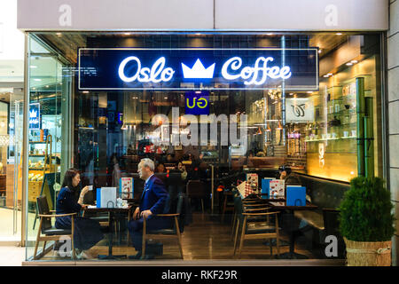 Tokyo, Ginza, night. Looking in through glass front of the Oslo Cafe with mature formally dressed Japanese couple having a coffee at window table. Stock Photo