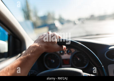 A man driving a car, focus on the left hand held on steering wheel Stock Photo