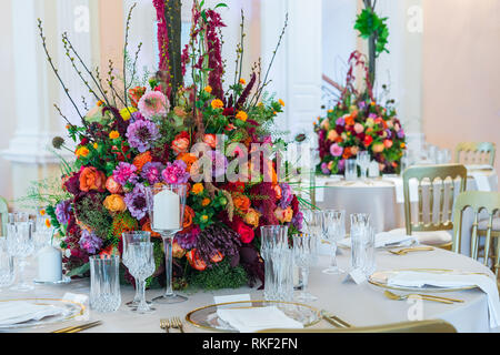 Wedding table decoration. Beautiful bouquet of flowers on the table, next to plates, crystal glasses and plates Stock Photo