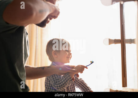 Father and son cleaning teeth together Stock Photo