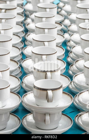 White coffee cups with plates stand stacked in a row Stock Photo