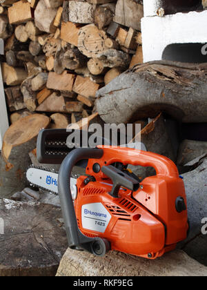 Brand new Husqvarna T425 Chain Saw on woodpile ready fro use Stock Photo