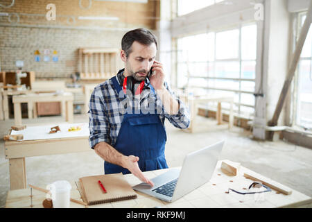 Frowning man talking to customer on phone Stock Photo