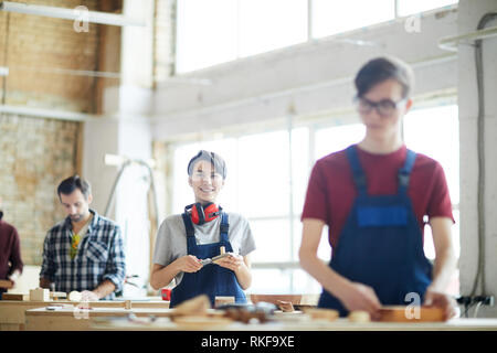Cheerful lady working in carpentry shop Stock Photo