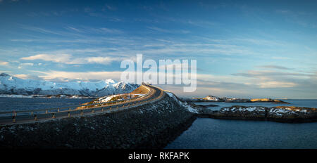 Atlantic Ocean Road - Atlanterhavsvegen in winter sunny day. Famous high bridge over the sea called Storseisundbrua and beautiful snowy mountains in a Stock Photo