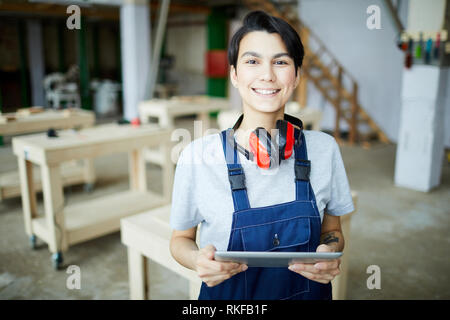 Smiling female carpenter with tablet Stock Photo