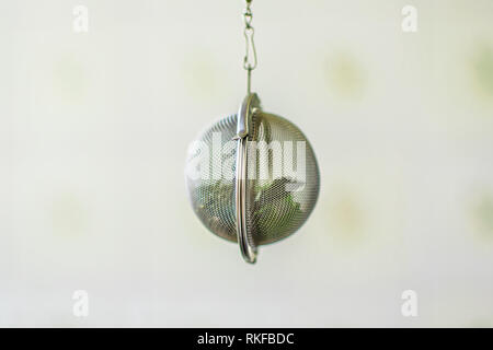Suspended metal tea infuser with dried leaves of green tea and mint on clean background Stock Photo