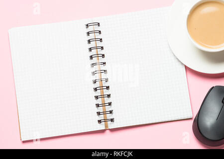Office workplace with notepad, coffee cup and mouse on pink desk. Stock Photo