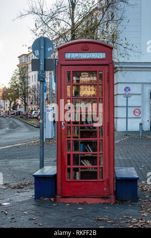 Berlin-Wilmersdorf. BucherboXX.Tiny lending library in Red Telephone box donated by British allies in front of Fehrbelliner Platz 4 (Lancaster House) Stock Photo
