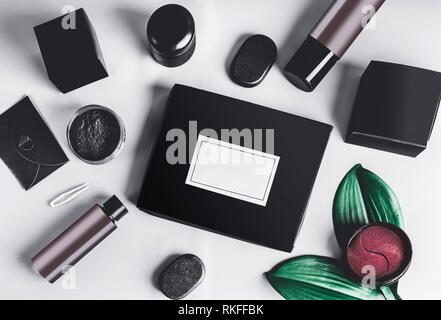 Black beauty box and various black and brown cosmetic product in jars and bottles with branding mock up.  Eye patch. Snail mucin or charcoal cosmetic  Stock Photo