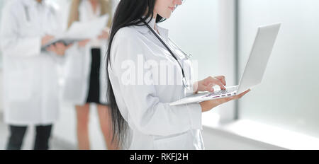 smiling doctor therapist uses a laptop while standing in the hallway of the medical center Stock Photo