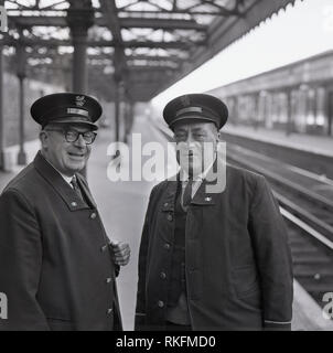 1968, two uniformed British Rail station staff, a foreman and ticket collector standing together on a platform at Blackheath railway station, Blackheath, London, England, UK. Stock Photo