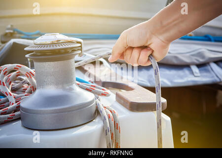 Winch and sailor's hands on sailboat. Stock Photo