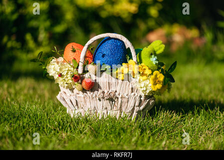 Easter gifts and eggs in small basket in small basket on green grass Stock Photo