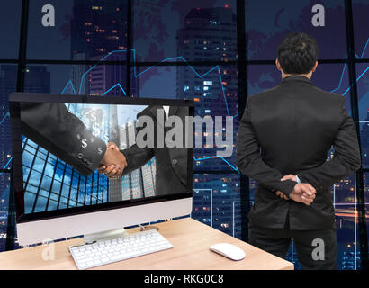 the computer on the wood table with Hand shake between businessman at the screen in front of the glass window over on the trading graph over the blurr Stock Photo