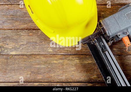 Safety helmets for workplace construction or industrial use to prevent accidents and air nail gun nailer tool from working. Stock Photo