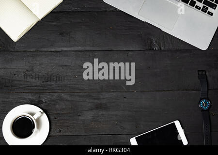 Work place flat lay on black background. Laptop, note pad, coffee and cell phone on lack wood texture, top view Stock Photo