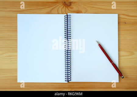White blank page of an opened notebook and a red pen on wooden background Stock Photo