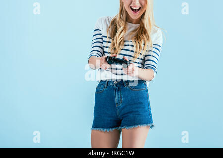 Cropped view of laughing young woman with gamepad isolated on blue Stock Photo