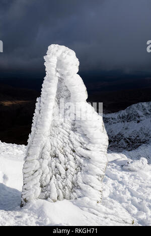 Ice covered marker stone at top of Watkin Path on Mount Snowdon in winter snow in Snowdonia National Park. Rhyd Ddu, Gwynedd, North Wales, UK, Britain Stock Photo