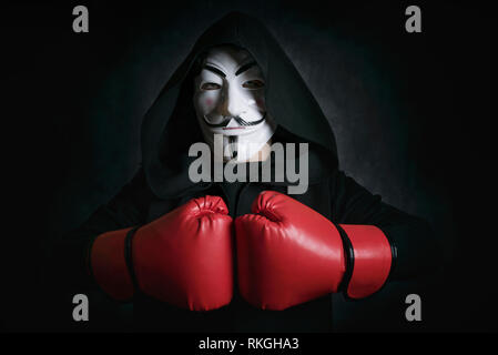 man with Masking anonymous and boxing gloves on black background Stock Photo