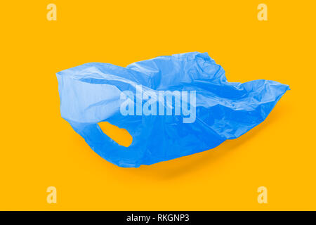 Floating empty blue plastic garbage bag on complementary orange background, Stock Photo