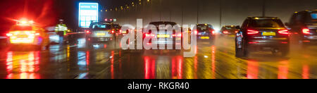 Panoramic web banner motion blurred photograph of traffic at in night in the rain on a British motorway with police officer and car Stock Photo